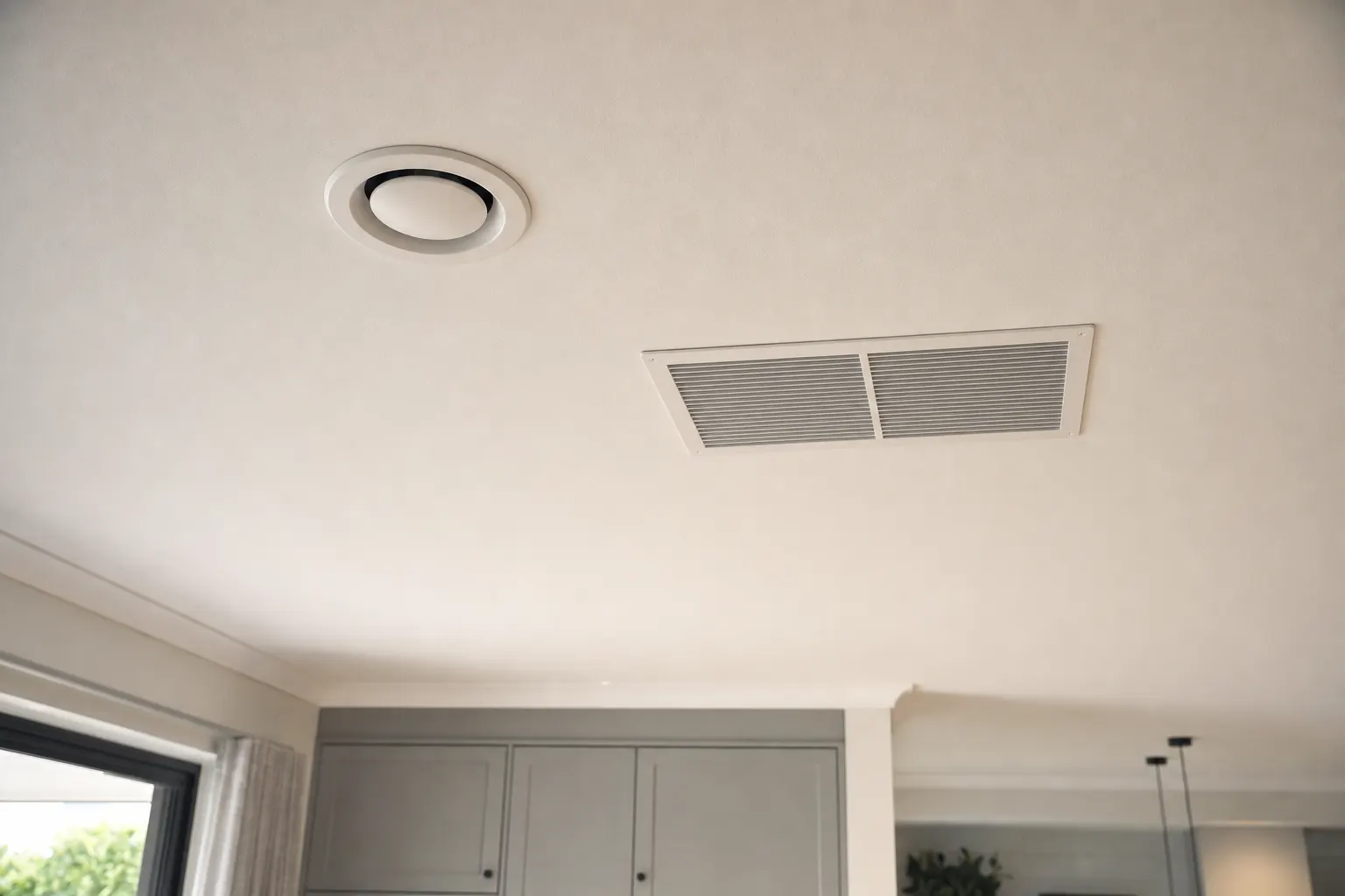 Round supply diffuser and return-air grille in a warm living space